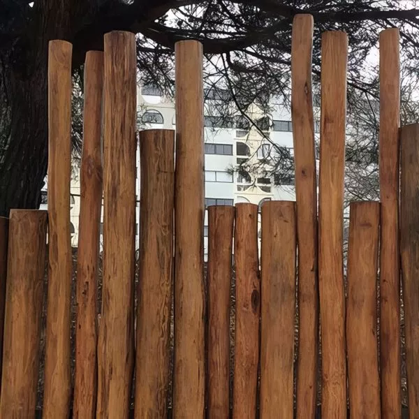 clôture créée avec des poteaux ronds en bois de robinier dans un jardin